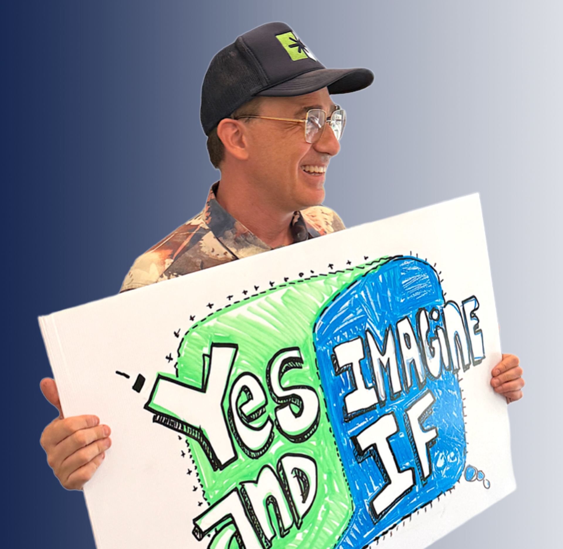 Craig Provost holding a hand-drawn 'Yes And / Imagine If' sign